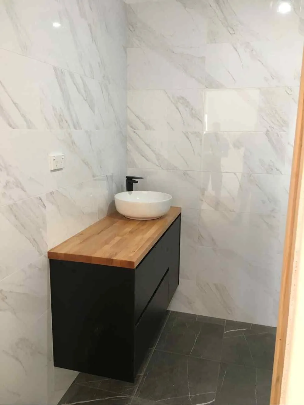 Modern bathroom vanity with marble wall tiles installed by AH Plumbing & Maintenance