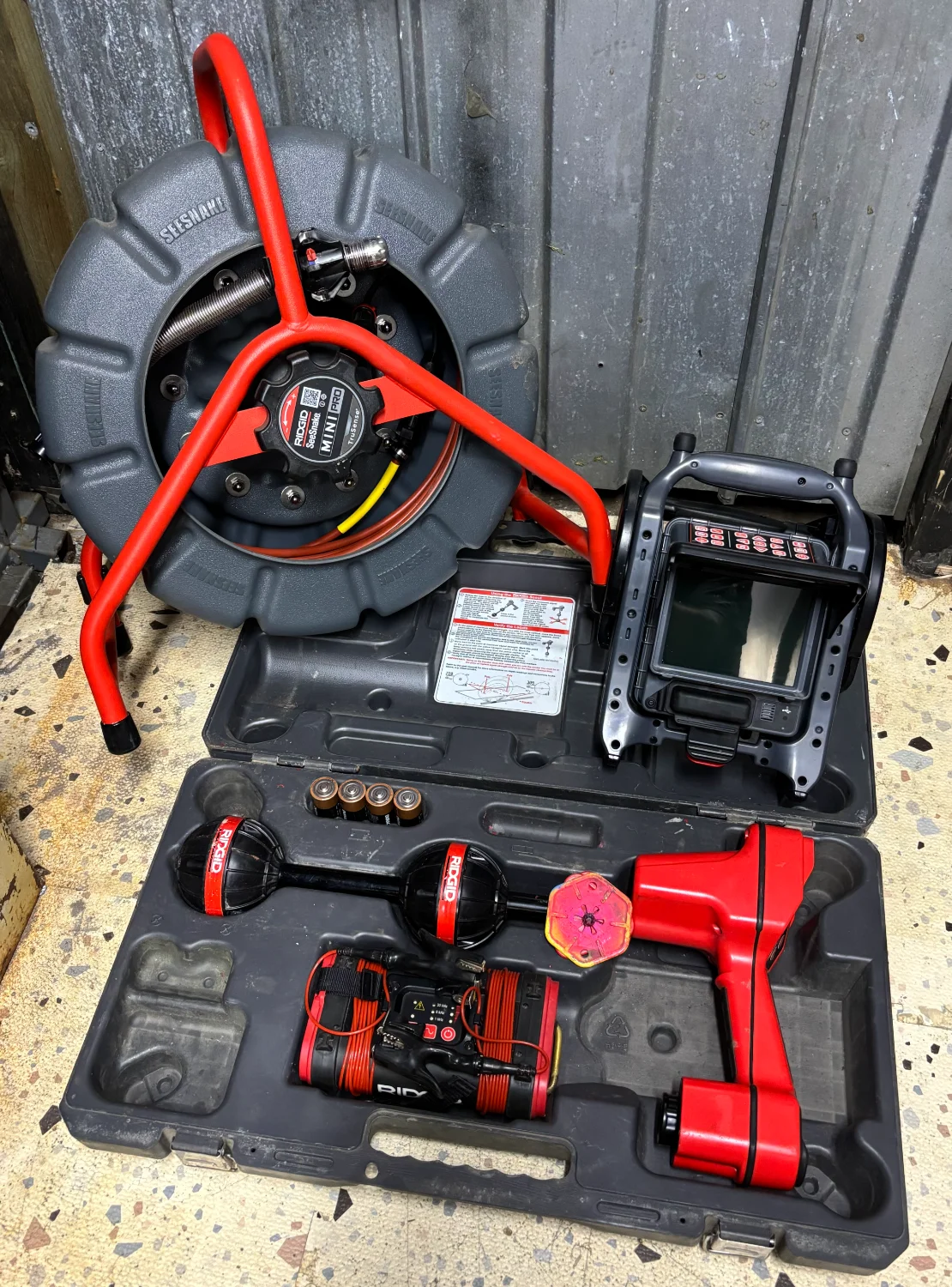 RIDGID SeeSnake CCTV drain camera and locator equipment laid out in cases on a workshop floor