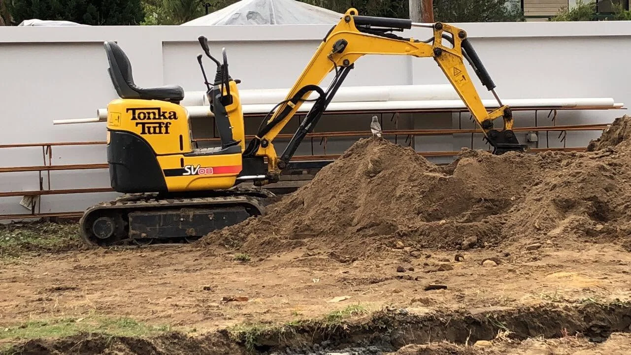 Tonka Tuff mini excavator working beside freshly laid pipes at a residential excavation job