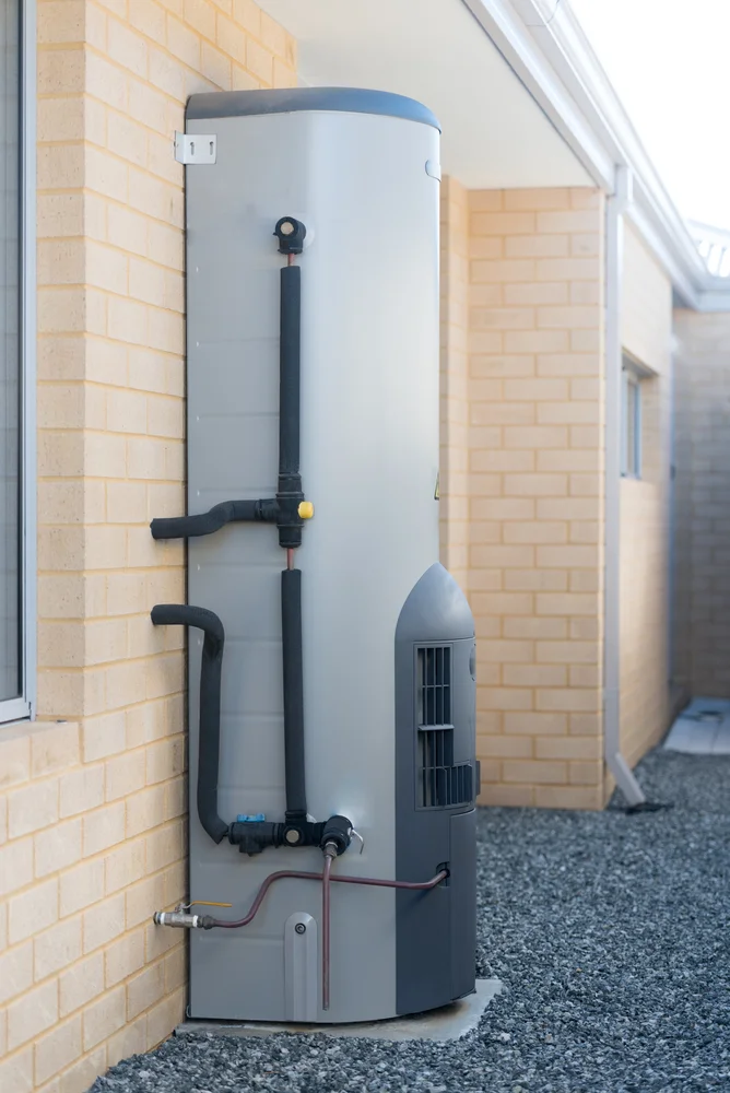Heat pump hot water system installed against a brick wall at a residential property