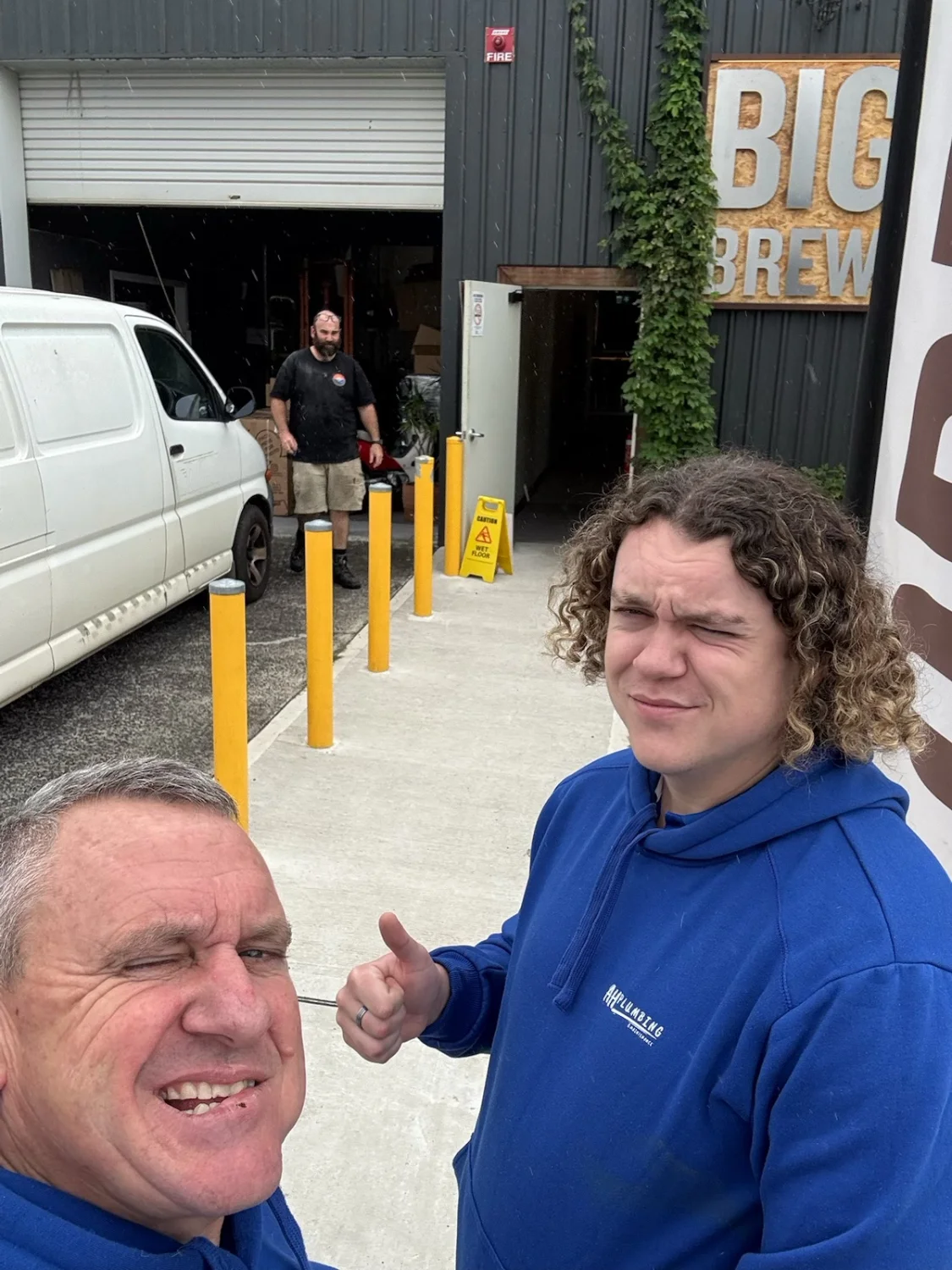 AH Plumbing & Maintenance team members taking a selfie outside a warehouse