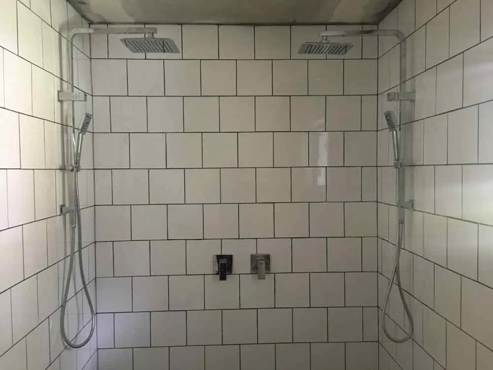 Dual rainfall shower heads installed in a tiled shower cubicle by AH Plumbing & Maintenance