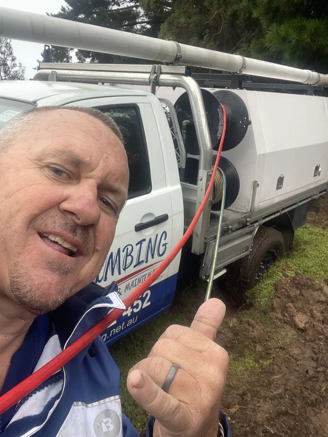 AH Plumbing & Maintenance plumber beside a branded service ute