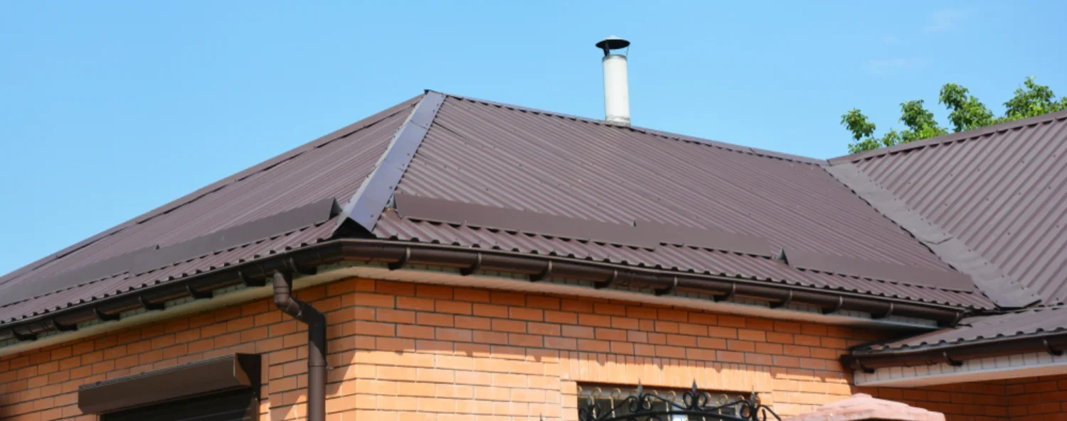 Corrugated metal roof with gutter and downpipe on a brick home