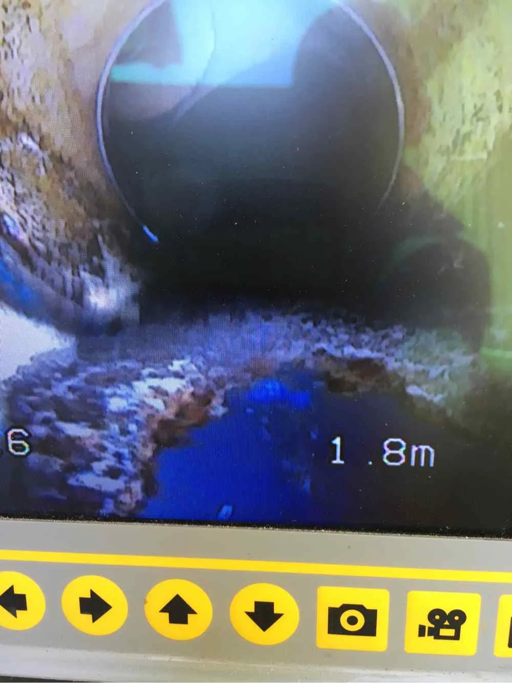 CCTV pipe inspection screen showing internal pipe damage and blockage at 1.8 metres depth